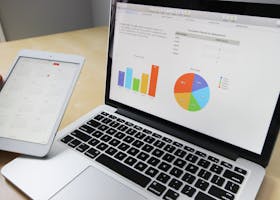 Laptop displaying charts and graphs with tablet calendar for data analysis and planning.